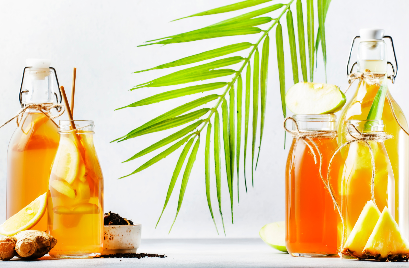 kombucha starters in jars with pineapple, lemon and ginger ingredients