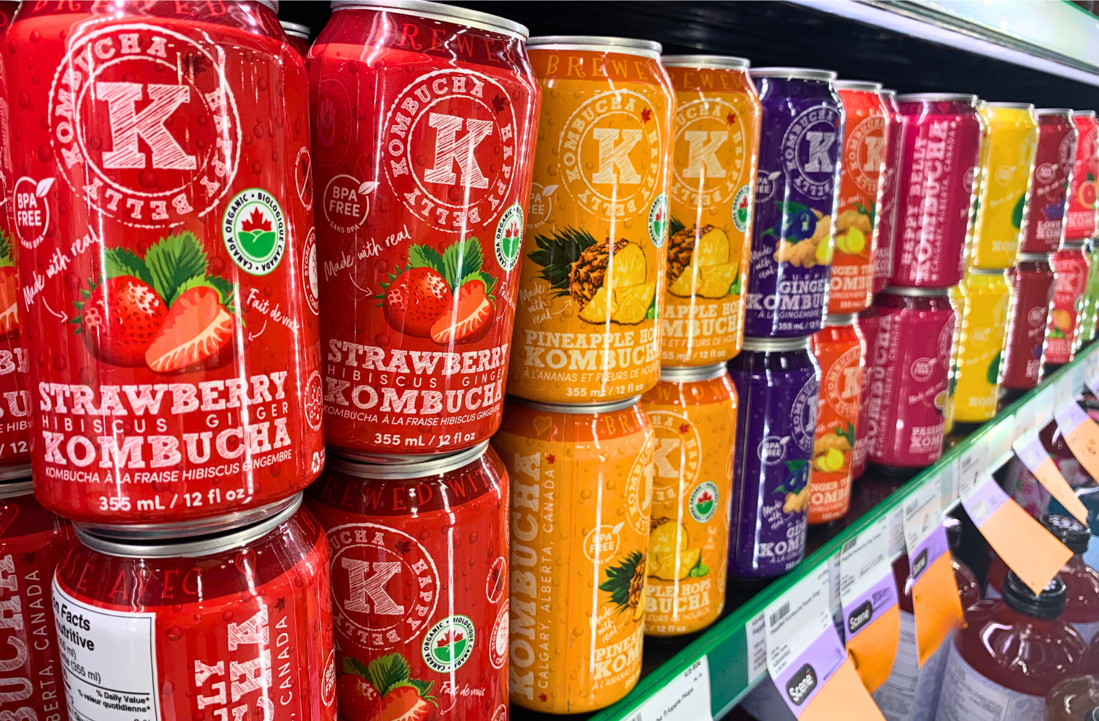 happy belly kombucha assorted flavors cans in a grocery shelf or rack banner