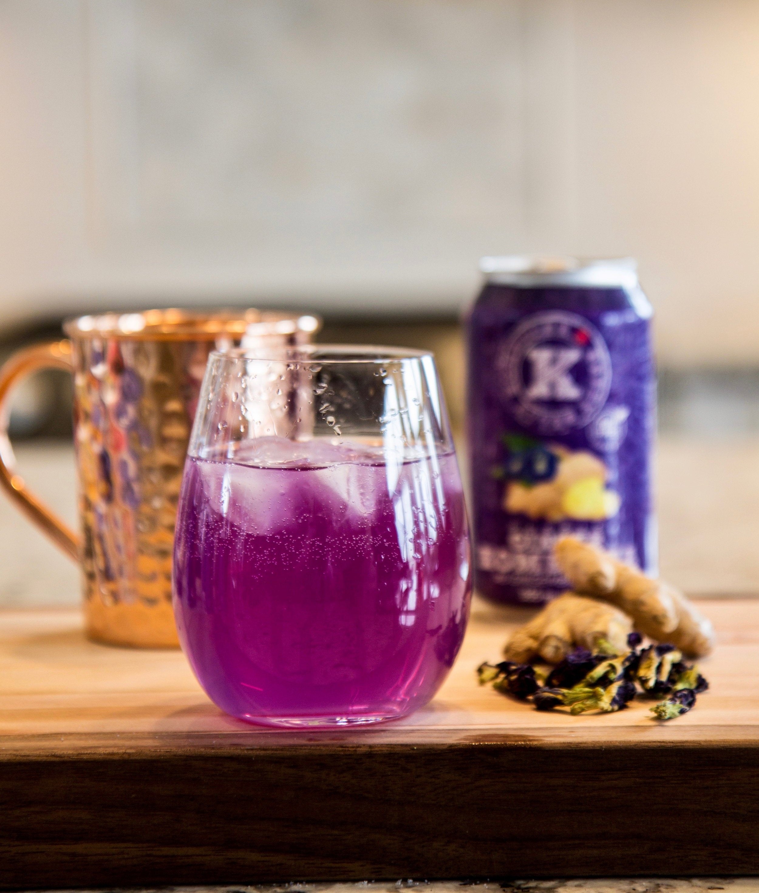 purple potion cocktail with happy belly kombucha purple ginger flavor can in background