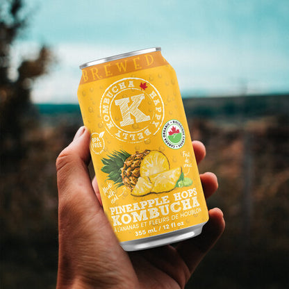 holding a can of happy belly kombucha pineapple hops kombucha brewed flavor