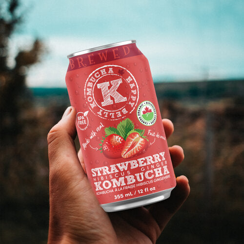 holding a can of happy belly kombucha strawberry hibiscus ginger kombucha brewed